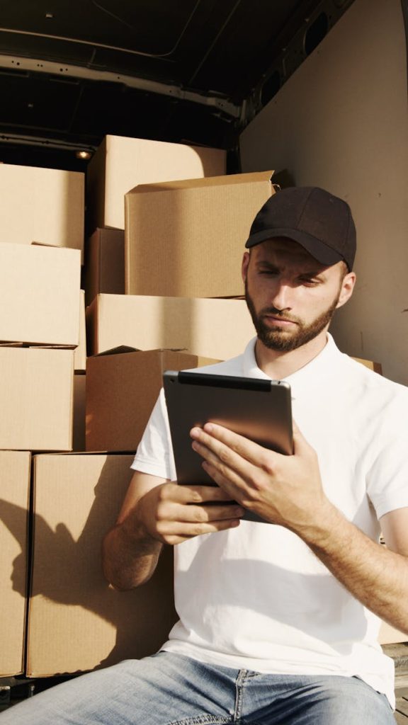 Mastering the First Impression: Your intriguing post title goes here Deliveryman using a digital tablet to manage packages in a van. Efficient courier service with boxes.
